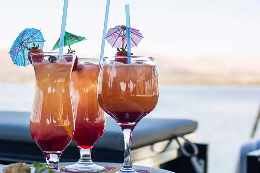 Two cocktails with paper umbrellas on a table by the water