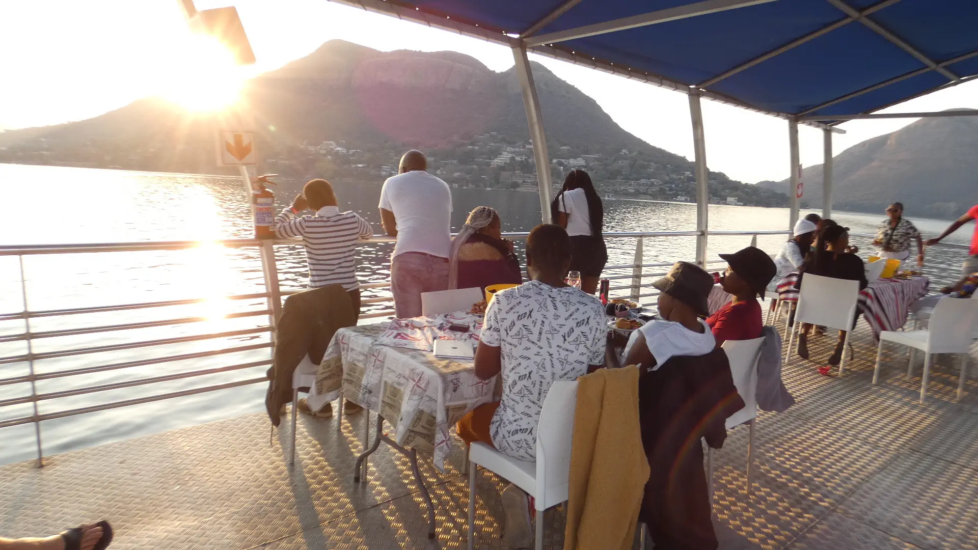 Guests at tables on deck as the sun drops behind the Magaliesberg